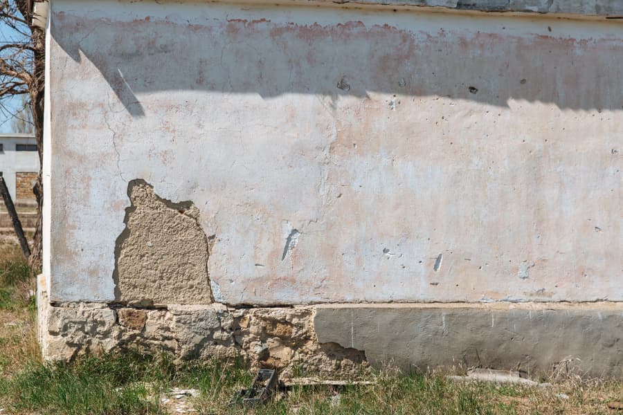 Foundation of slowing sinking building with a cracked and broken wall